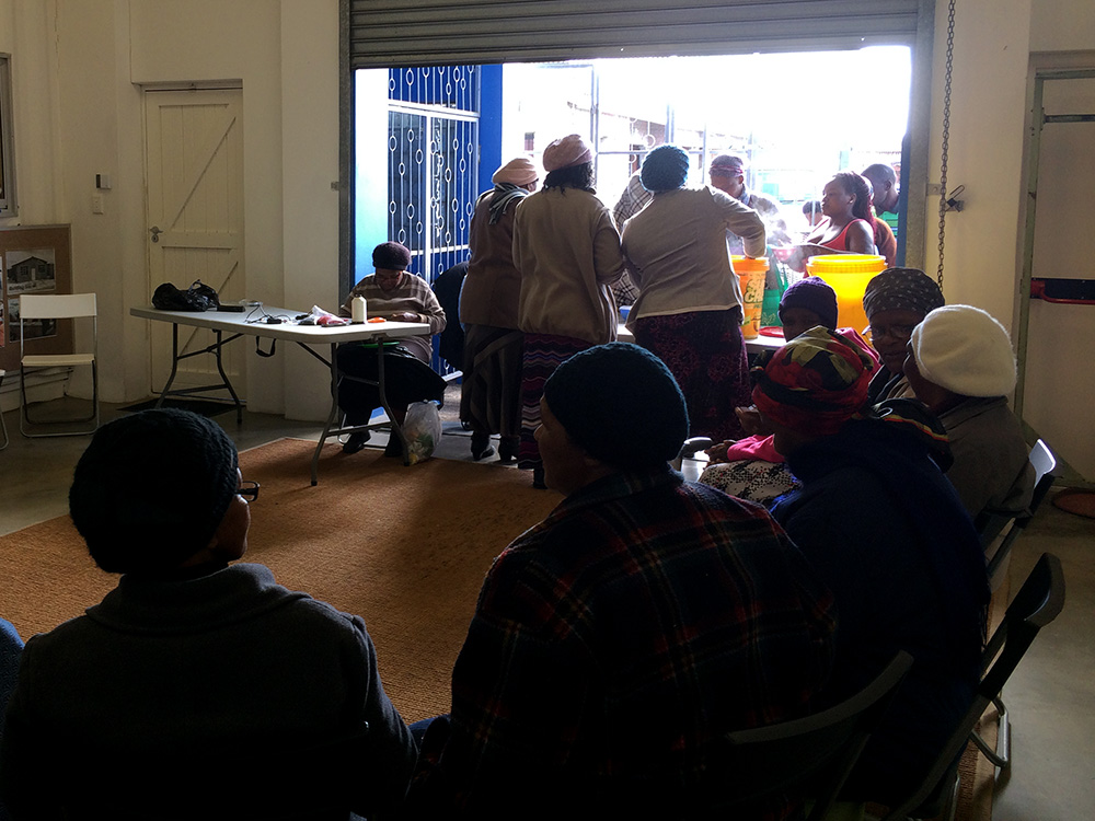 eKhaya eKasi also provides space for social services and community meetings. Women in the skills development program serve soup to residents for the Meals on Wheels program. The Elders seated in this photo meet to discuss their burial society. Burial societies are designed to help ease the costs of a funeral by operating on a monthly contribution. The estimate is that two thirds of households in townships participate. The ability to give their family a dignified burial is a significant cultural event and expectation for most black South Africans.